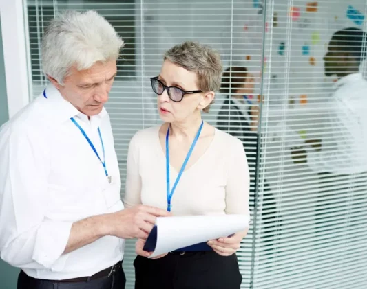 Credentialing vs Contracting in Healthcare Healthcare professionals discussing documents in an office, highlighting the importance of understanding credentialing vs contracting in healthcare.
